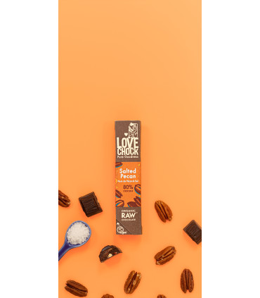 Barrita de chocolate negro 80% de nuez pecana y sal marina sobre fondo naranja