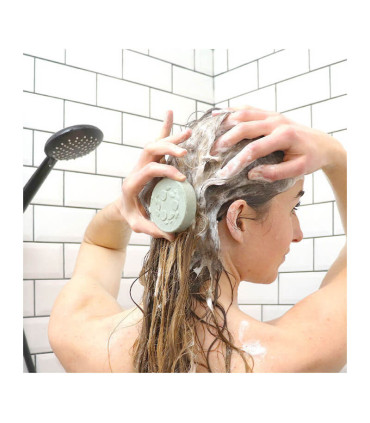 Mujer en la ducha usando el champú sólido natural para cabello graso con espirulina de lamazuna